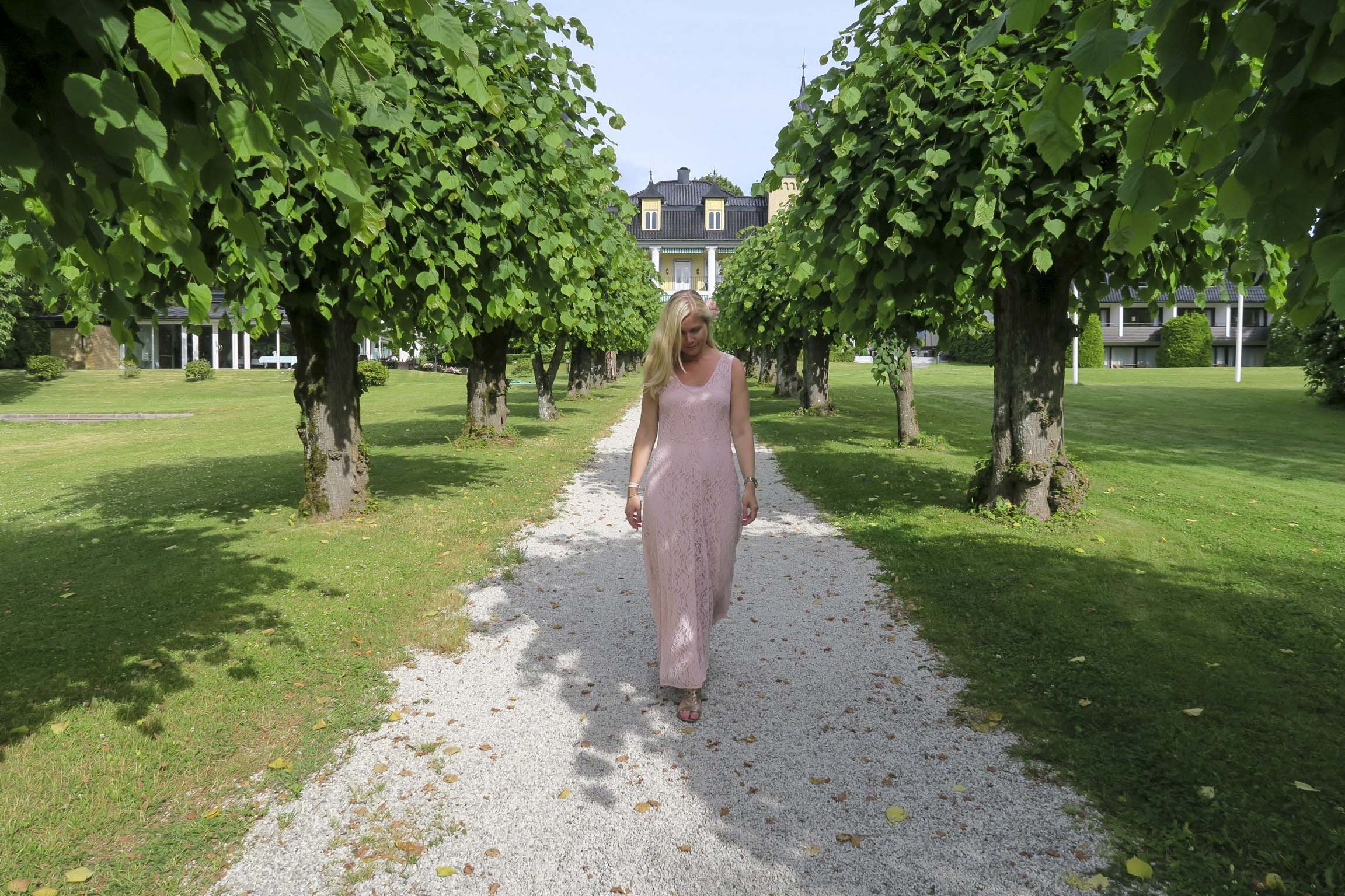 Dame i rosa kjole i hotellets allé