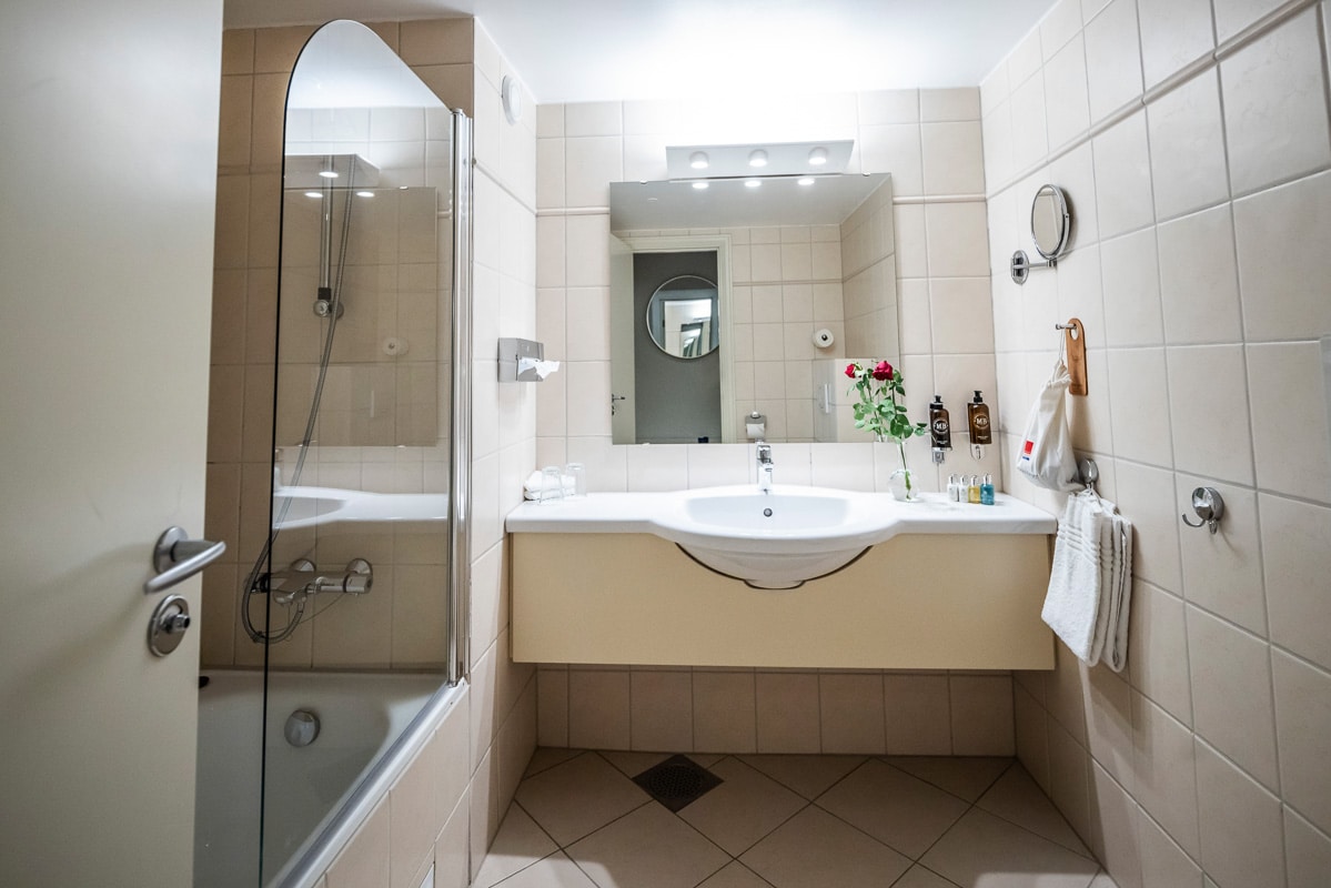 Bad på Refsnes Gods hotell i Moss med fliser, dusj og badekar med fine detaljer.