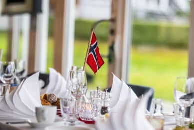 Dekket bord med norske flagg under 17. mai-frokost på Refsnes Gods i Moss – herskapelig hotell ved Oslofjorden.